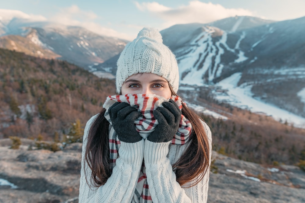 A woman standing in a hilly area enjoying the snow