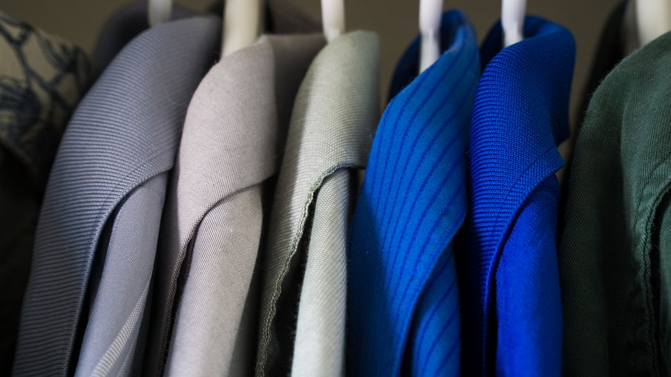 A closet full of different colored shirts 