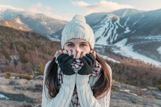 A woman standing in a hilly area enjoying the snow 